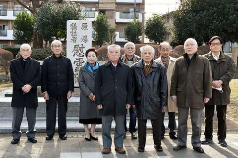 慰霊碑の手前に立つ、東京都原爆被害者協議会の役員ら。