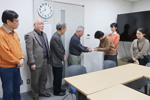 会議室のドアの前で、岩波書店労組のみなさんから寄付金を受け取る東友会幹部。