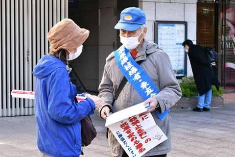 たすきをかけ署名板を持った被爆者と通行人が会話している。