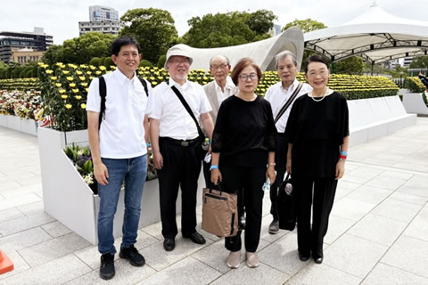 広島平和公園内、原爆死没者慰霊碑前に設置された献花台の前に立つ、6人の集合写真。