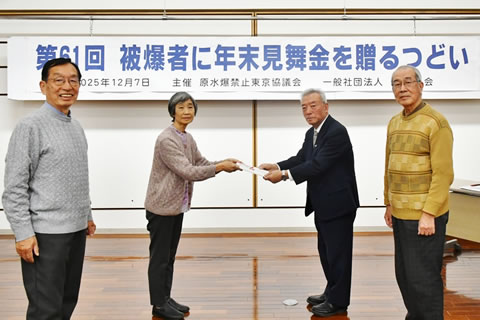 会場前方に立つ、見舞金の封筒を手渡す東京原水協の2名と受け取る東友会の2名。