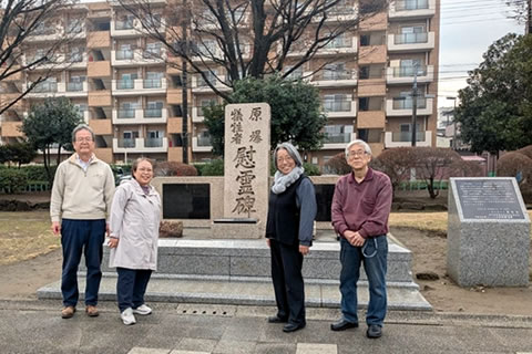 慰霊碑の前に立4人の事務局員。