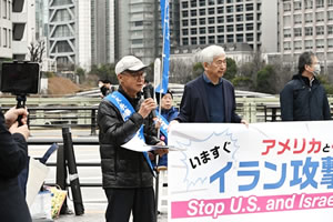 街頭に立ち、マイクを使って通行人に訴える、タスキを掛けた被爆者。